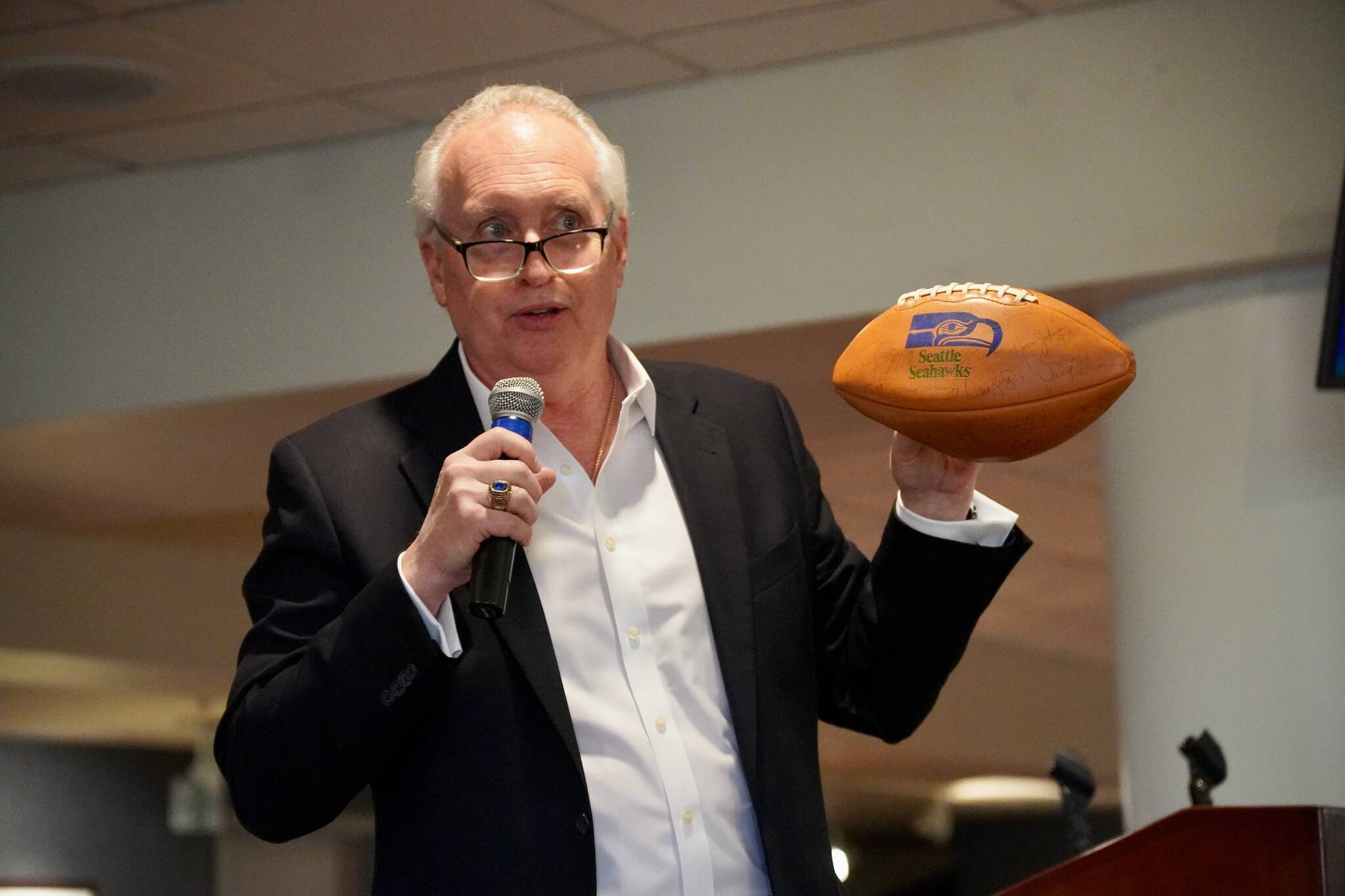 Steve Raible auctioning off a Seahawks football from 1983.