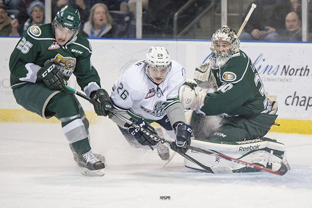 The Thunderbirds' Nolan Volcan charges the puck between the Silvertips' Cole MacDonald