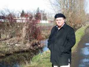 Kent resident Mike McCaughan stands Wednesday next to Mill Creek near his home on Kennebeck Avenue