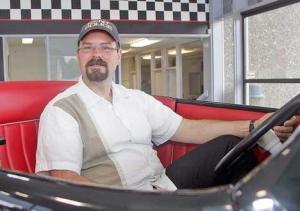 Kent Police Chaplain Pat Ellis grins behind the wheel of a classic car during a Cops with Cancer Fundraiser this summer in Kent.
