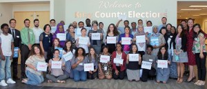 King County Elections Director Julie Wise (second from right) stands with community partners holding up vote signs in different languages.