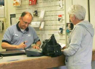 Post office retail associate Jim Kohler weighs and prepares Crystal Wright's letters for delivery Wednesday at the downtown Kent post office. The U.S. Postal Service is considering selling the facility