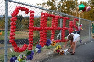 Susan Tostenrude adds a bouquet of flowers to a memorial honoring the late Chase Stancil at Kentridge High School on Friday evening. Family