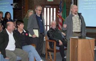 Shawn Seeger of Burien addresses a group of local state senators Saturday with a question about cutting protection for wild salmon. Seeger and more than 100 people attended a town hall meeting in Kent to discuss shortfalls in the state budget.