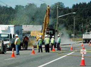 Local emergency officials and Puget Sound Energy workers stand near the site of a ruptured natural-gas line late Wednesday morning. The smoky substance in the air is dust being kicked up by the escaping gas.