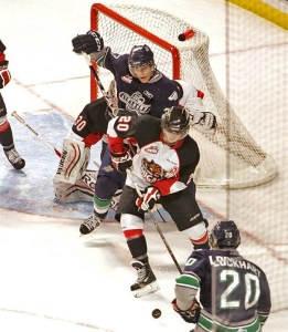Thunderbird Chance Lund fights to rebound the puck against Cougar Troy Bourke