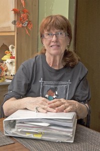 Sally Goodgion sits with the binder that holds memories of all her visiting students. The binder holds more than 40 sets of photographs