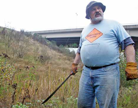 Doug Hill points out some of the invasive plants Tuesday that grow on the hill of the South 277th Street overpass just above the Green River Road. Hill plans to become a Green Kent steward to oversee the area for the city.
