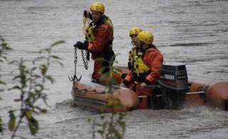 A King County rescue unit combs the Green River in search of a sunken car and two missing boys Friday. A 16-year-old driver of the car escaped. She called 911
