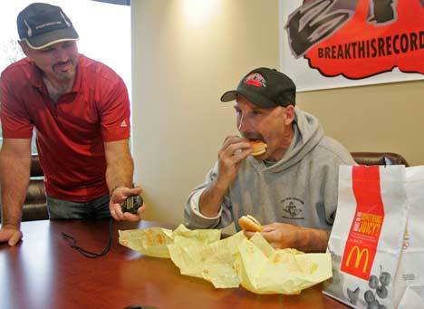 Breakthisrecord.com owner Jeff Huffman attempts to set a new milestone for eating three cheeseburgers while Mike Chaffeur watches the clock. Huffman accomplished the mission