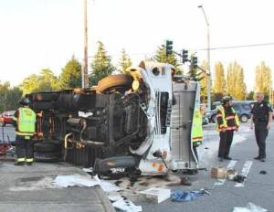 Local emergency personnel stand beside a demolished panel truck following a two-vehicle accident on the West Valley Highway that sent both drivers to the hospital with serious injuries.