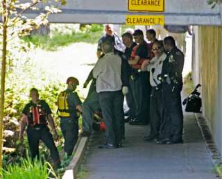 Officers from Kent and Tukwila fire departments and Tukwila Police Department gather under the Strander Boulevard bridge in Tukwila on the banks of the Green River after the Kent Fire Department boat retrieved the body of a man from the water Thursday afternoon.