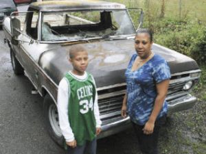 Kelly Carroll and her son Robert stand with Carroll’s burnt-out truck Wednesday in Kent.  The truck made Carroll’s charity organization