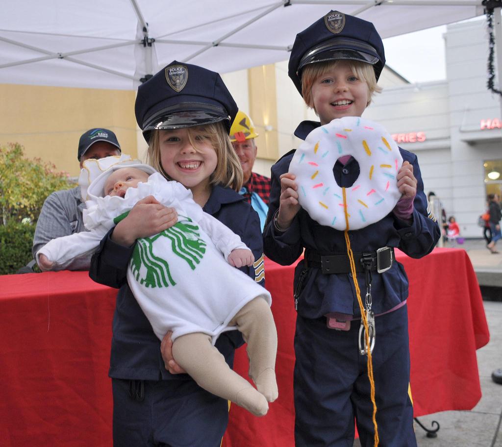 Lillia Smith, 6, and Isabelle Smith, 8, of Kent, completed their police officer costumes with help from their 2-month-old sister Cinthia, who was a cup of Starbucks coffee. HEIDI SANDERS, KENT REPORTER