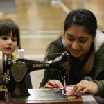 Kentwood High School student Harneet Manai shows Cambrie Smith, 4, how to sew.