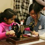 Kent-Meridian High School student Diane Yeyat helps Navya Parmar, 9, sew. DENNIS BOX, Reporter