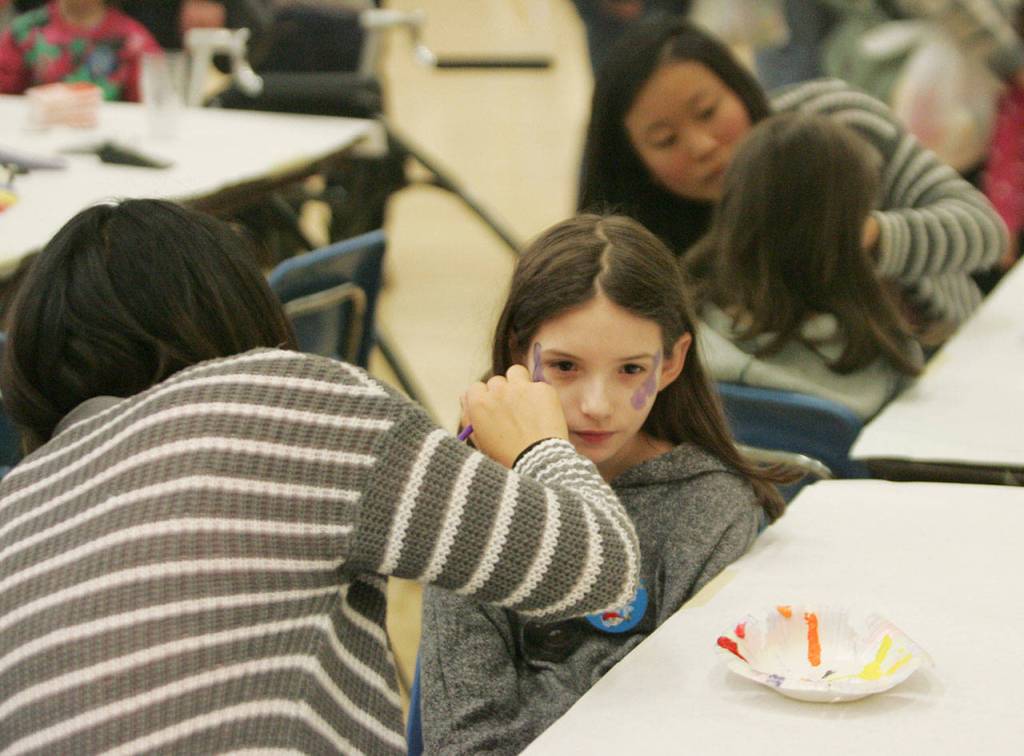 Aimee Phung, a Kent-Meridian High sophomore, paints 9-year-old Abigail Gonzalez&rsquo; face. Gonzalez is a student at Kent&rsquo;s Sunrise Elementary. DENNIS BOX, Reporter