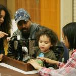 Dominic, 6, left, watches Kent-Meridian High sophomore Octiviah Patterson teach his his brother Elijah Mead, 3, to sew, as their dad, Tony looks on. DENNIS BOX, Reporter