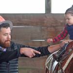 Tomas Alvarez guides 2-year-old Victoria, as she rides a horse in the stable at Reber Ranch during Quota Cares Western Days last Saturday. MARK KLAAS, Kent Reporter