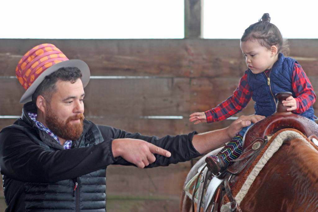 Tomas Alvarez guides 2-year-old Victoria, as she rides a horse in the stable at Reber Ranch during Quota Cares Western Days last Saturday. MARK KLAAS, Kent Reporter