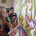 First-grader Caden Smith, left, and third-grader Avneet Singh paint a mural during a birthday party for Emery the Emergency Penguin, the mascot for the county&rsquo;s E-911 program, at Kent&rsquo;s Daniel Elementary School last Friday. HEIDI SANDERS, Kent Reporter