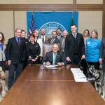 Animal care and protection advocates, lawmakers and dogs gathered as Gov. Inslee signed Sen. Joe Fain&rsquo;s humane treatment for dogs legislation. COURTESY PHOTO