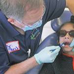 Dr. Chris Delecki examines Sohang Nannar during the SmileMobile&rsquo;s visit to Kent Elementary School on Monday. MARK KLAAS, Kent Reporter