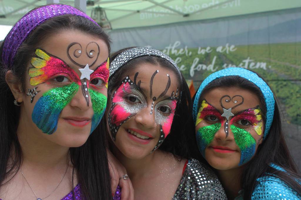 Freshly face-painted Amneea Idrahim, left, Rafal Flayyih, middle, and Zahraa Mohammed enjoy the celebration the festivities in the plaza on Saturday. MARK KLAAS, Kent Reporter