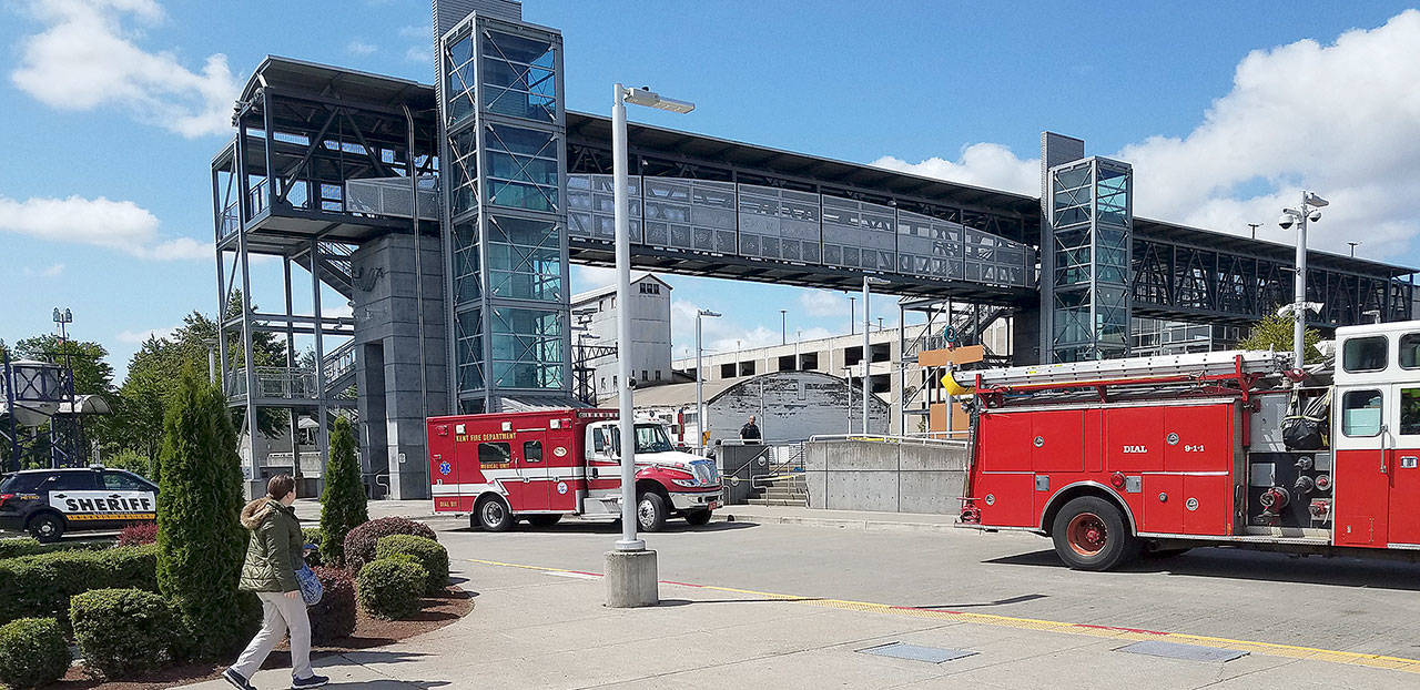 A passerby looks on as Puget Sound Fire crews and King County Sheriff&rsquo;s Office officials investigate the death of a woman hit by a freight train on Sunday near Kent Station. Courtesy Photo/Kenneth Smysor