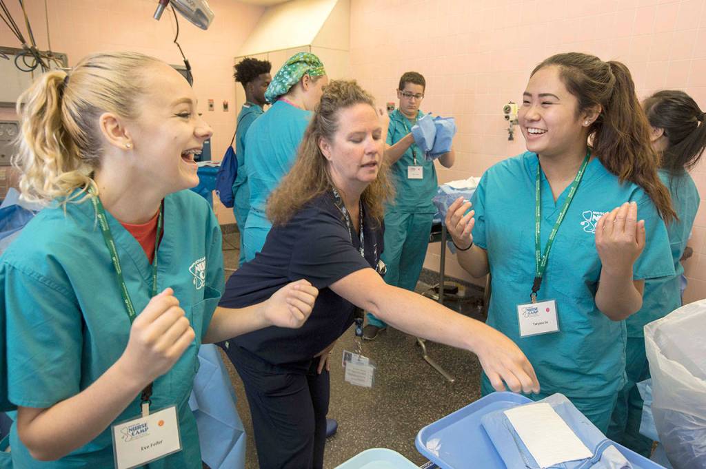 Eve Feller, of Washington High School in Parkland, left, and Tatyana So, of Kent, right, share a laugh as they &ldquo;gown up&rdquo; at MultiCare Nurse Camp on July 19. The five-day camp, now in its 14th year, is designed to get high school students interested in health care careers, particularly nursing. COURTESY PHOTO, Patrick Hagerty