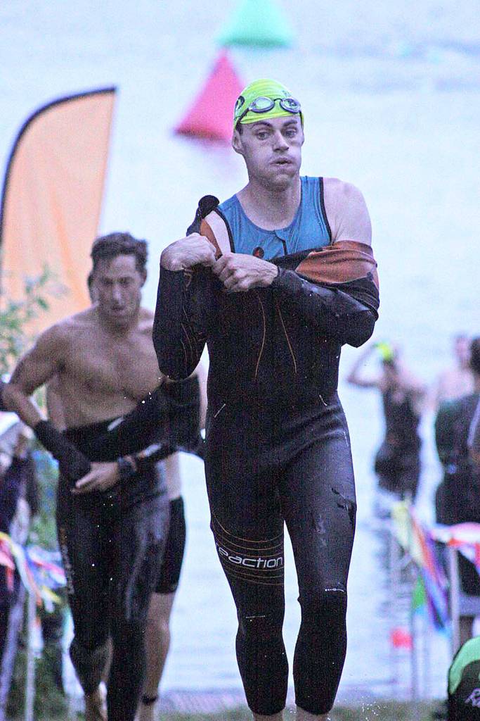 Andrew Richards, who finished second in the men&rsquo;s sprint wave division, tries to shed his wet suit after leaving the Lake Meridian waters in the opening swim segment en route to the transition area for the bike leg. MARK KLAAS, Kent Reporter