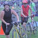 Lydia Fenton, left, and Daniel Neumann, roll their bikes from the transition area during the Lake Meridian Triathlon. MARK KLAAS, Kent Reporter