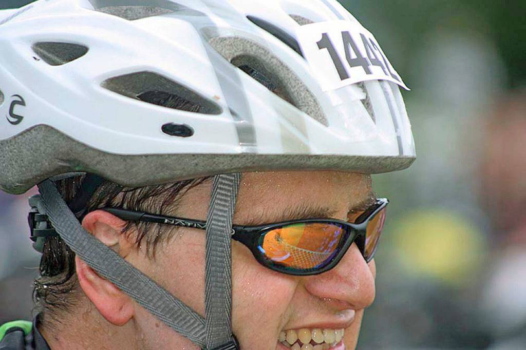Clockwise, from top, Paul Hunziker, an Olympic-course competitor, breaks into a smile as he buckles up for his bike ride. MARK KLAAS, Kent Reporter