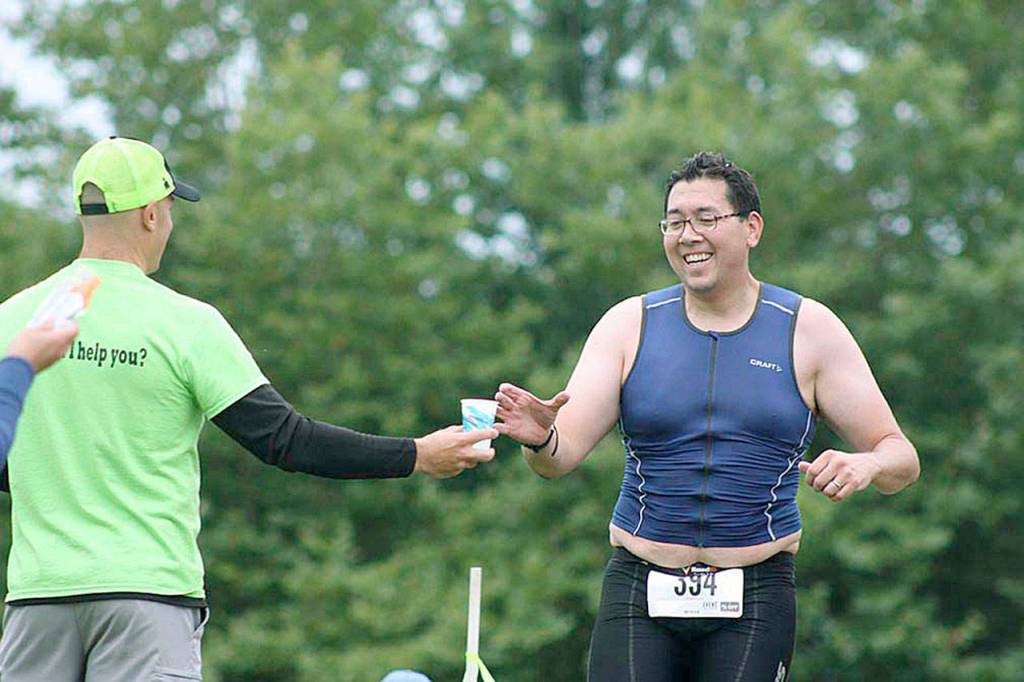 Leigh Tsuji, a men&rsquo;s sprint wave competitor, reaches for water as he begins the third leg, a 3.1-mile run. MARK KLAAS, Kent Reporter