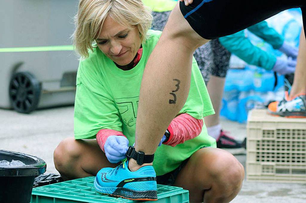 A race volunteer retrieves a timing chip strap from a competitor at the finish line. MARK KLAAS, Kent Reporter