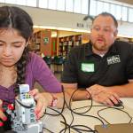 Derek Dykman, a business banker with Denali Federal Credit Union, oversees the robotic work of Fatema Metwally, an eighth-grader at Meridian Middle School, in the Kentridge High School library at the STEM event for girls on Monday. MARK KLAAS, Kent Reporter