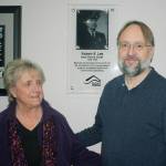 Vicki Schmitz, daughter of former Kent Police Chief Robert E. Lee, and Dietrich Schmitz, grandson of Lee, pose next to a photo of Lee at the police station lobby. STEVE HUNTER, Kent Reporter