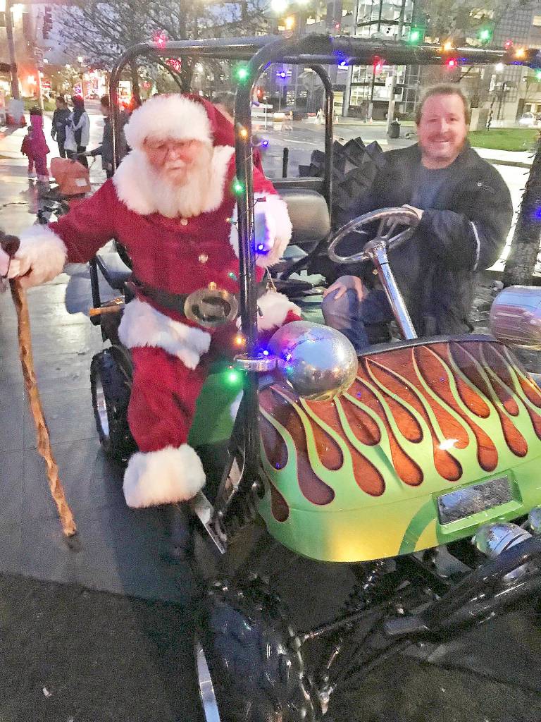 Shawn Ralph and a suped-up golf cart guide Santa to the square to greet children and help light the tree. MARK KLAAS, Kent Reporter