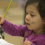 Mark McMillens 3-year-old daughter, Fern, applies some finishing touches to the robot they built from scrap during Kent Kids Arts Day. MARK KLAAS, Kent Reporter