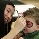 Cindy Tan applies face paint to the mask of Landon Detamore, 3, during Kent Kids Arts Day. MARK KLAAS, Kent Reporter