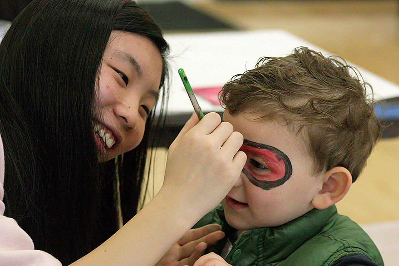 Cindy Tan applies face paint to the mask of Landon Detamore, 3, during Kent Kids Arts Day. MARK KLAAS, Kent Reporter
