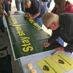 Bruce McDonald, foreground, and his 15-year-old daughter, Chloe, join others outside the accesso ShoWare Center on Saturday in signing a banner supporting the Humboldt, Saskatchewan junior hockey team. MARK KLAAS, Kent Reporter
