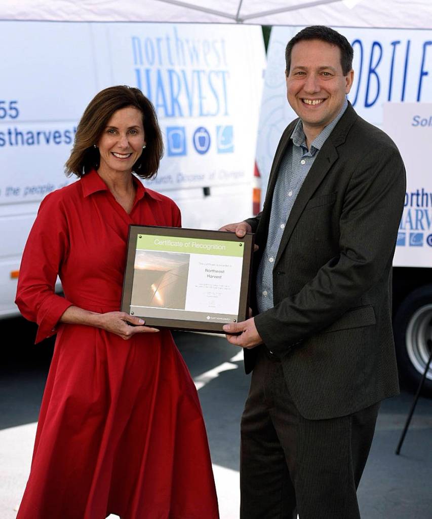 PSE President and CEO Kimberly Harris presents a plaque to Northwest Harvest CEO Thomas Reynolds. COURTESY PHOTO