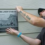 Mike Burngasser, of Industry Sign & Graphics, prepares to mount a historical plaque on the outside, front wall of the Domestic Abuse Womens Network (DAWN) administrative office and community services hub at 221 W. Gowe St., last Friday. The building, originally a horse stable in the early 1900s, became a supermarket and then a bank, among other things. MARK KLAAS, Kent Reporter