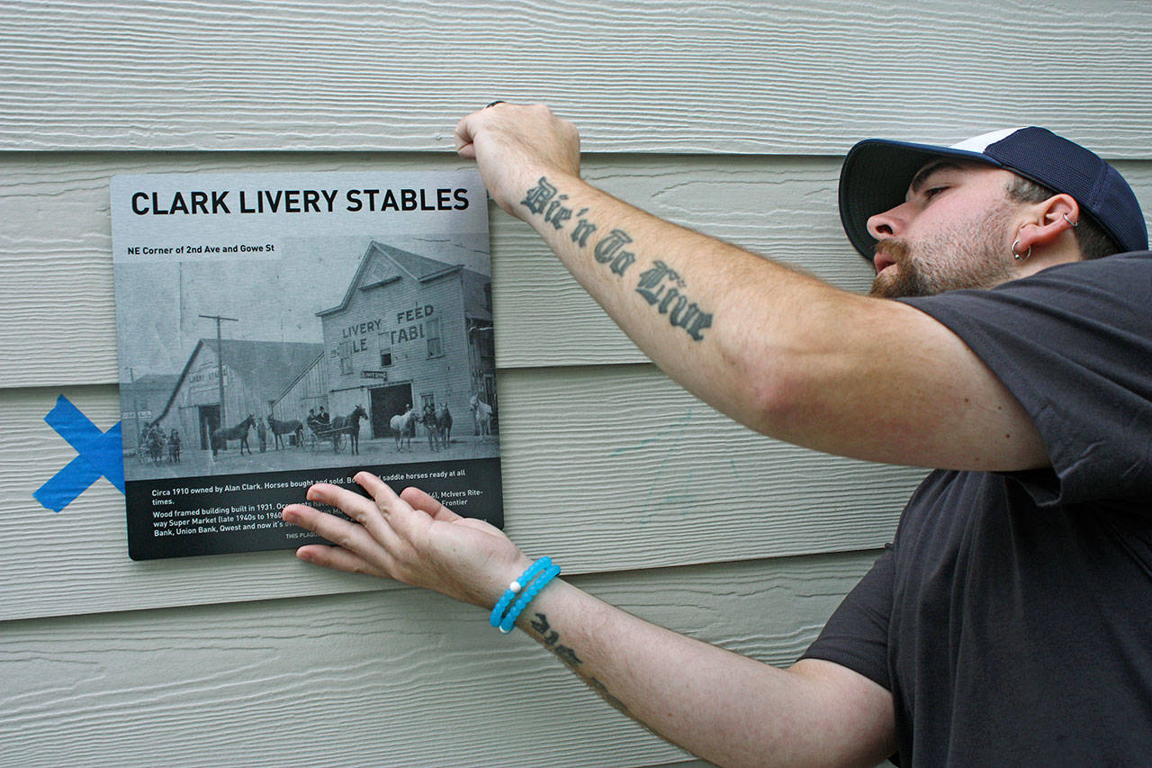Mike Burngasser, of Industry Sign & Graphics, prepares to mount a historical plaque on the outside, front wall of the Domestic Abuse Womens Network (DAWN) administrative office and community services hub at 221 W. Gowe St., last Friday. The building, originally a horse stable in the early 1900s, became a supermarket and then a bank, among other things. MARK KLAAS, Kent Reporter