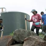Aimee Ingabire, middle, who immigrated from the Congo Republic, and youth from the Hillside Church 
weed around one of the cisterns at the Paradise Parking Plots Community Garden last Saturday.                                 MARK KLAAS, Kent Reporter