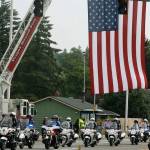 Police motorcyclists go under a flag displayed Tuesday along West James Street during a procession for Kent Police Officer Diego Moreno. STEVE HUNTER, Kent Reporter