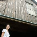Linda Person looks on from the base of the Sidetrack Distillery Barn, built from the design and materials of historical barns in the Green River Valley. Doors recovered from a late-1800 barn grace the building. The Persons own and operate the barn as a venue for public events, along with the Lazy River Farm that feeds their small distillery. MARK KLAAS, Kent Reporter