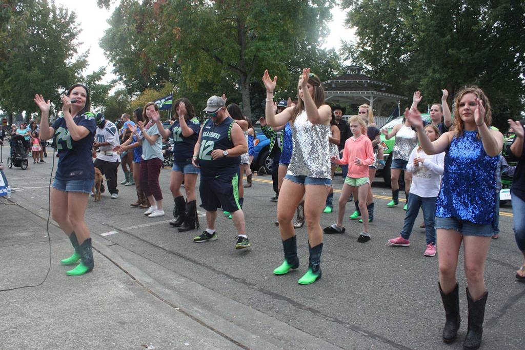 DeAnna Lee, left, and her Boot Boogie Babes teach fans how to line dance to a number during HAWKtoberfest. MARK KLAAS, Kent Reporter