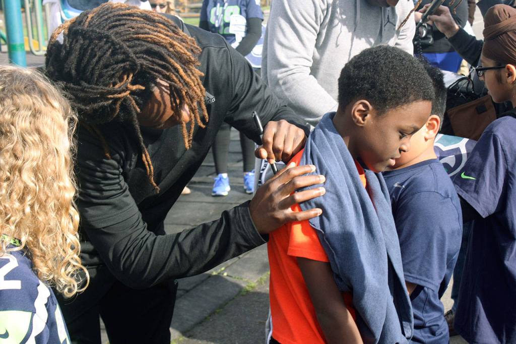 Seattle Seahawks cornerback Shaquill Griffin autographs a boys shirt on Tuesday at Park Orchard Elementary School in Kent. STEVE HUNTER, Kent Reporter